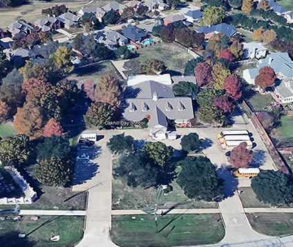 A wide shot of the secure, tree-lined Oakhill Day School campus and playground.