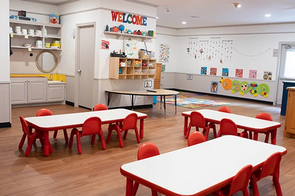 A nurturing teacher guides toddlers in the Ladybugs program at Oakhill Day School as they explore sensory materials in a bright classroom